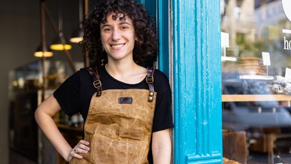Kvinde med forklæde smiler til kamera på cafe